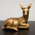 A golden sculpture of a deer with a lying pose.