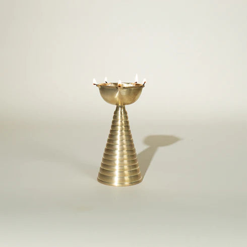 A gold-colored, conical brass diya