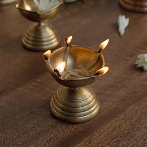 A gold-colored, conical brass diya