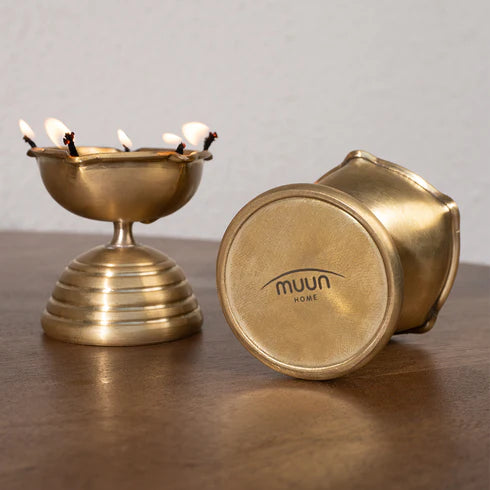 A gold-colored, conical brass diya