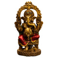 idol of lord ganesha with a golden finish, sitting and holding a modak in hand