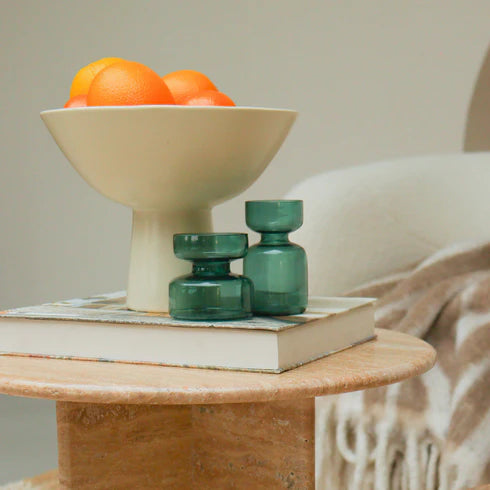 Ceramic bowl with oranges and  green vases nearby.