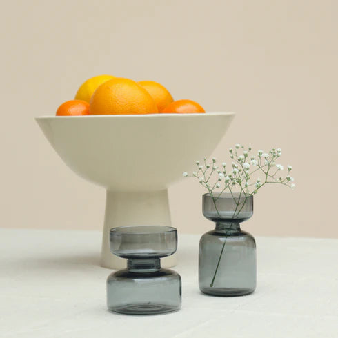 Fruit bowl with oranges and two gray glass vases.