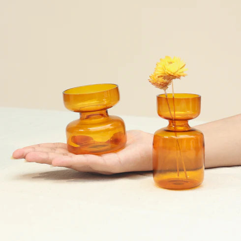 Two amber glass vases held in a hand 
