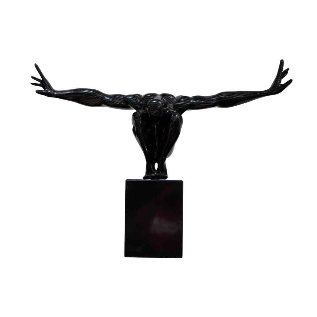 A black sculpture of a jumping man with outstretched arms, on a square base.