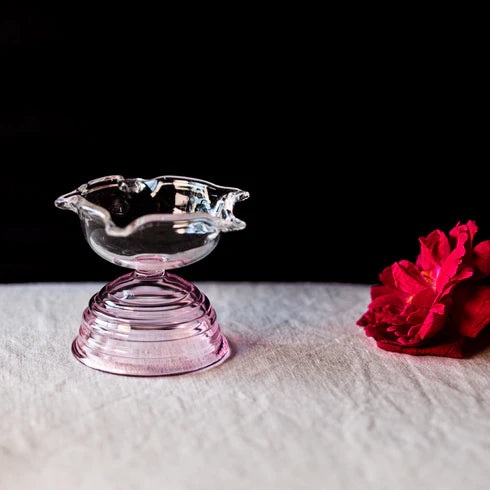 A clear glass diya with glass base