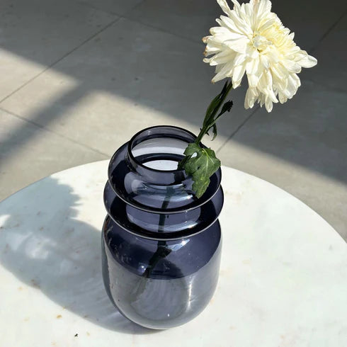 Dark glass vase with a white flower 