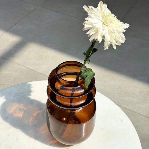 Brown glass vase with a white flower 