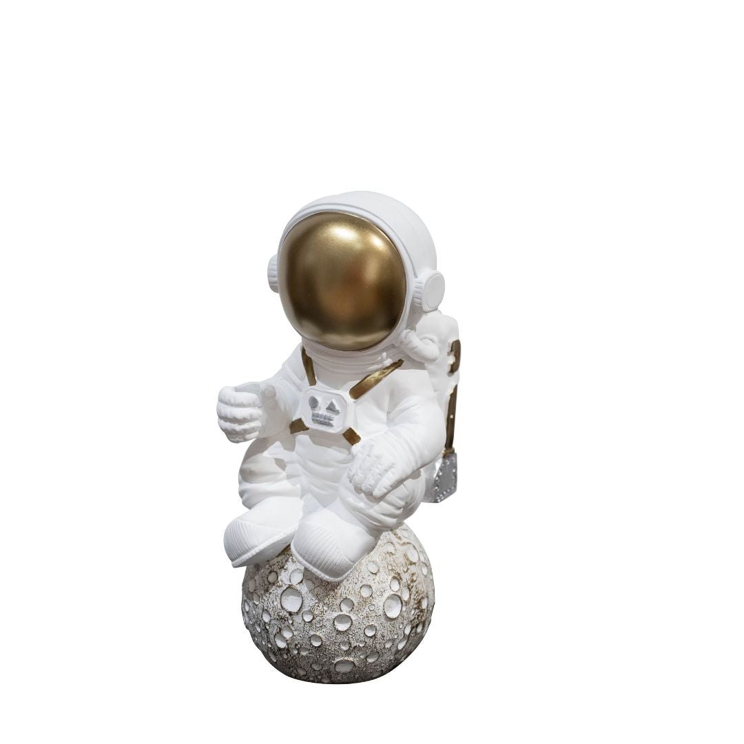 A sculpture of an astronaut in white and gold colors, sitting on a textured sphere