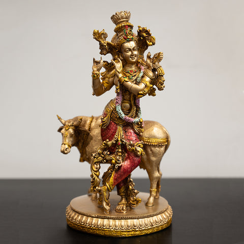 A golden sculpture of Lord Krishna sitting on a cow.
