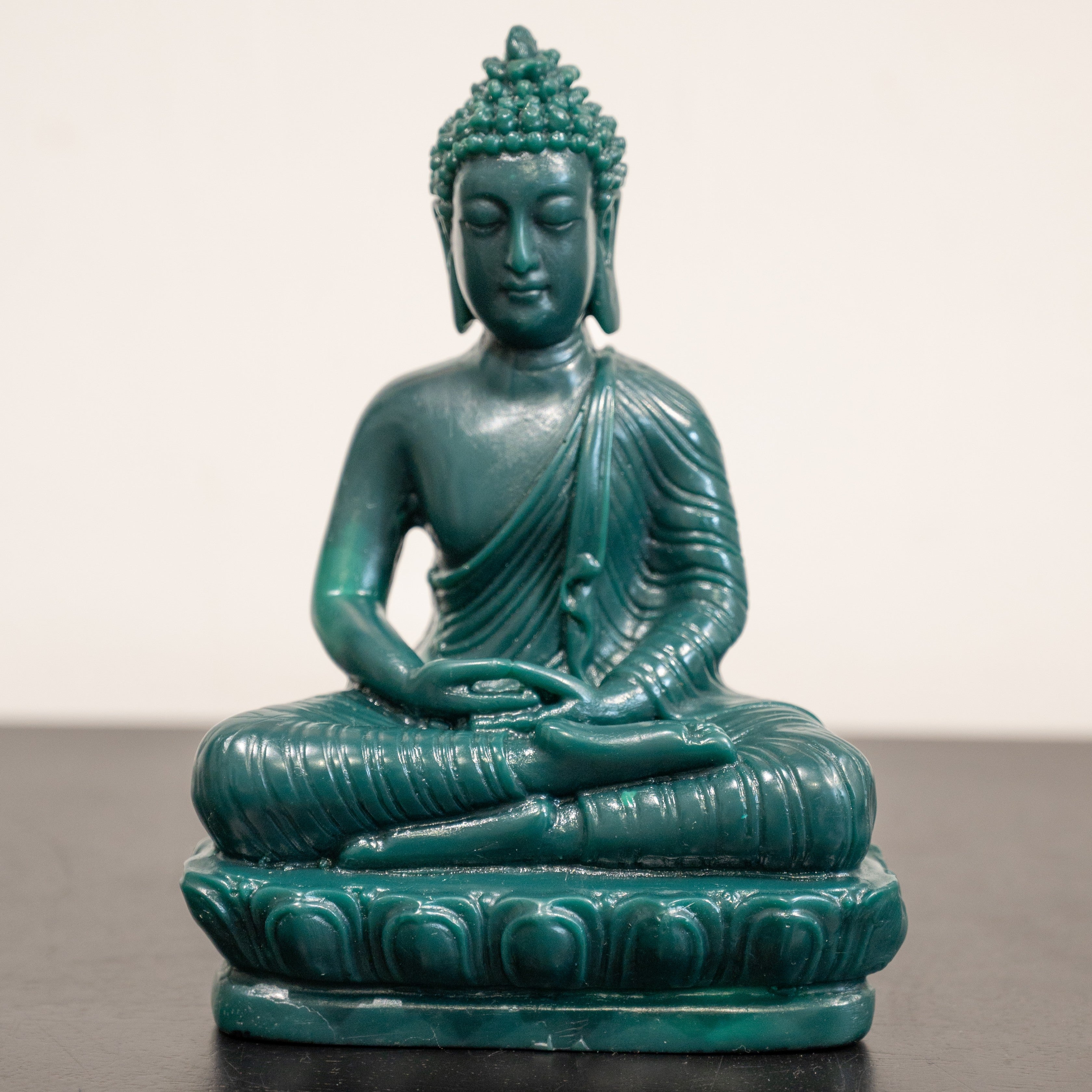A green sculpture of Buddha in a meditative pose.
