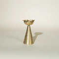 A gold-colored, conical brass diya 
