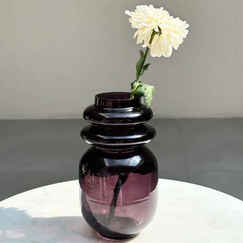 A dark lilac glass vase with a unique loop design