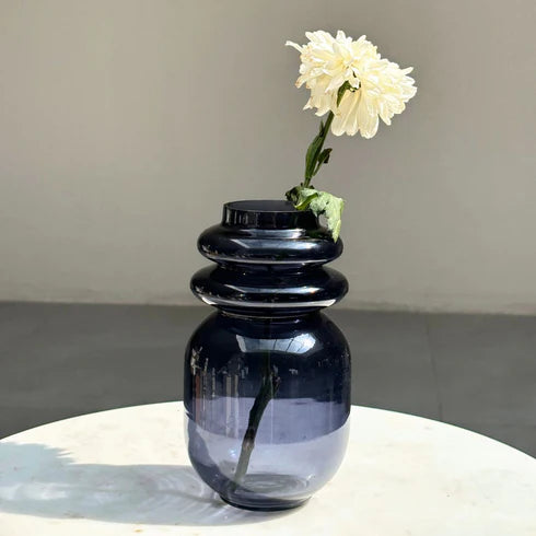 A slate grey loop glass vase with a flower on a table